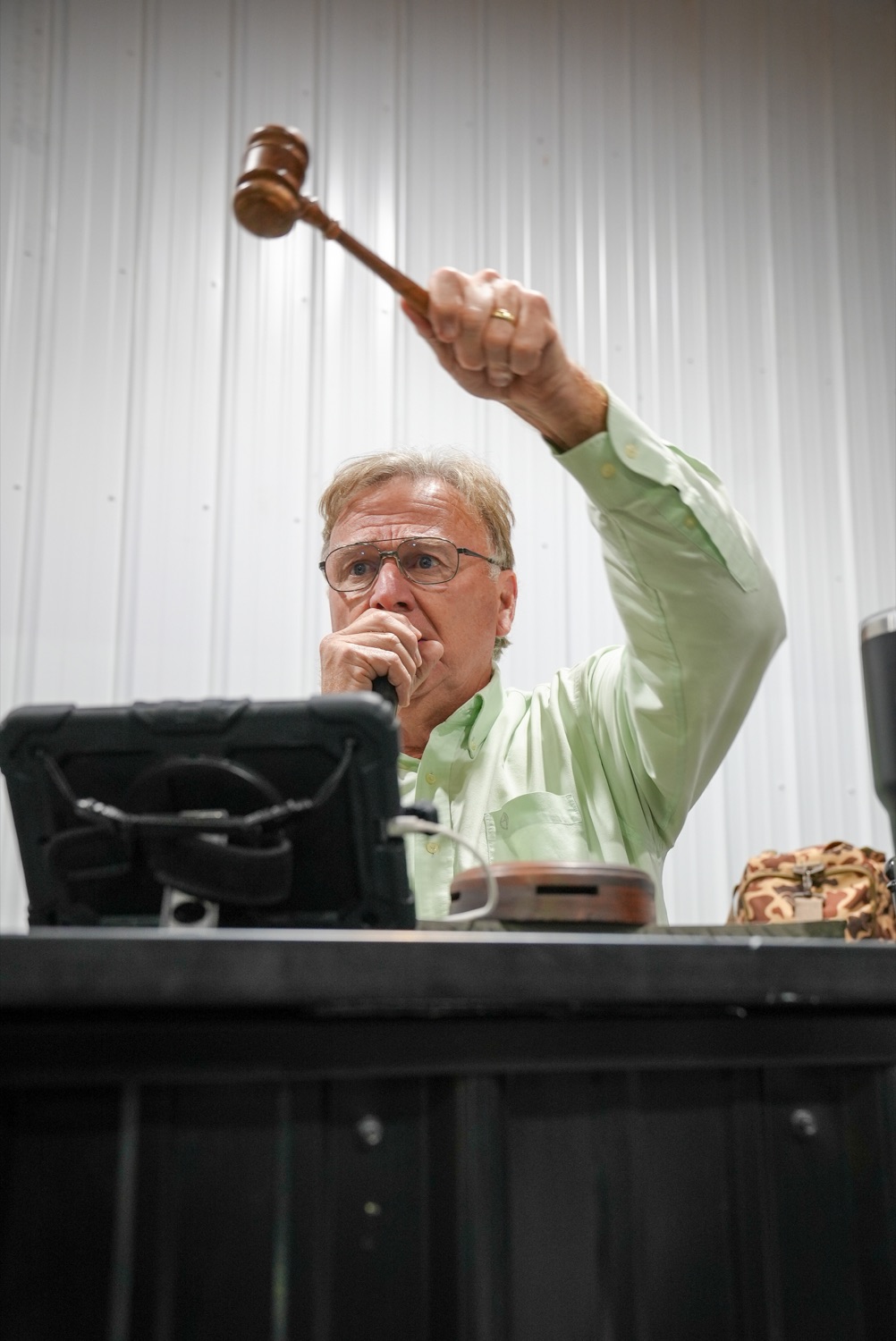 An auctioneer raising the gavel during live bidding at Delaware Auto Exchange
